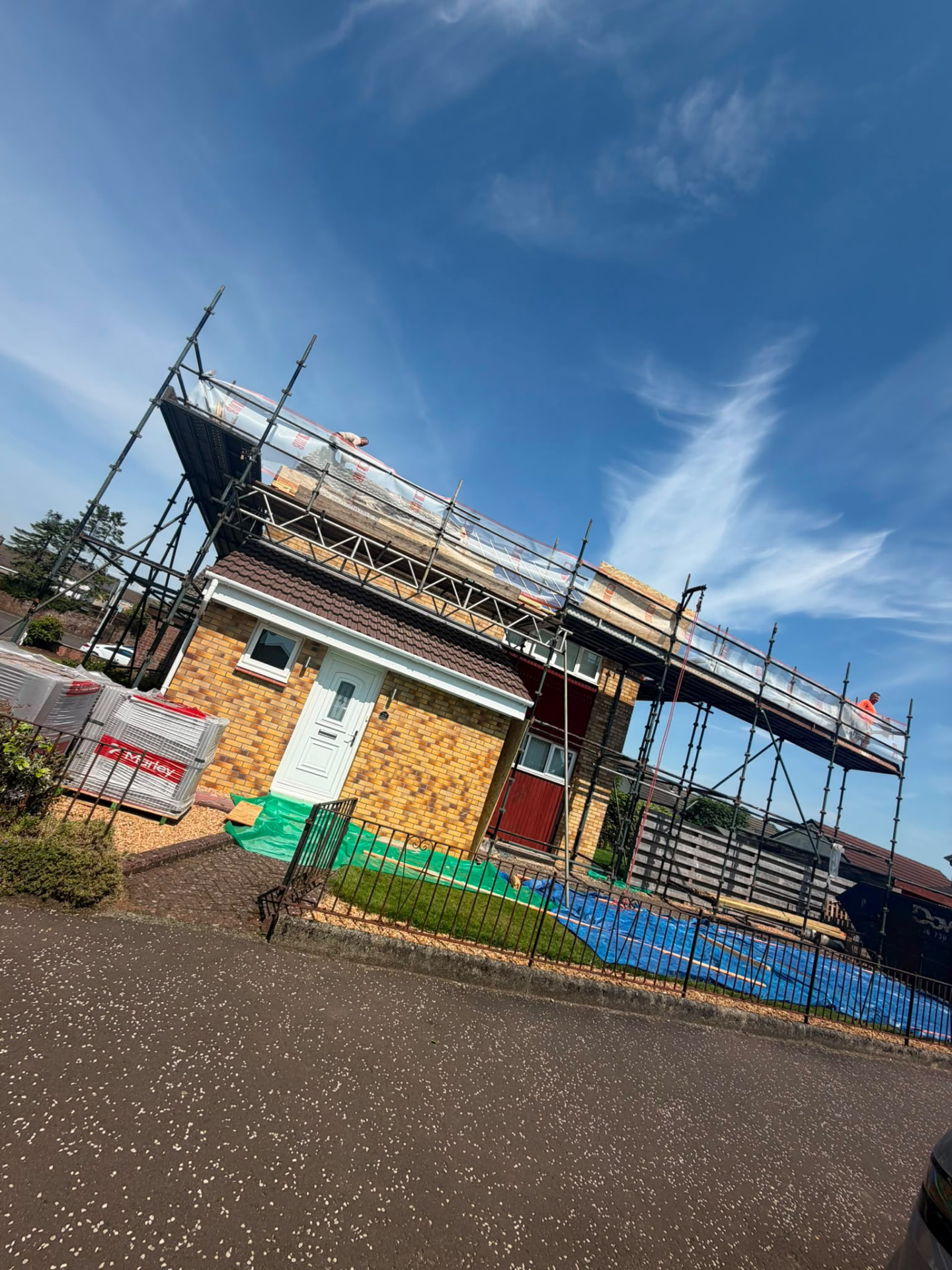 House under scaffolding with roofers fitting a new roof