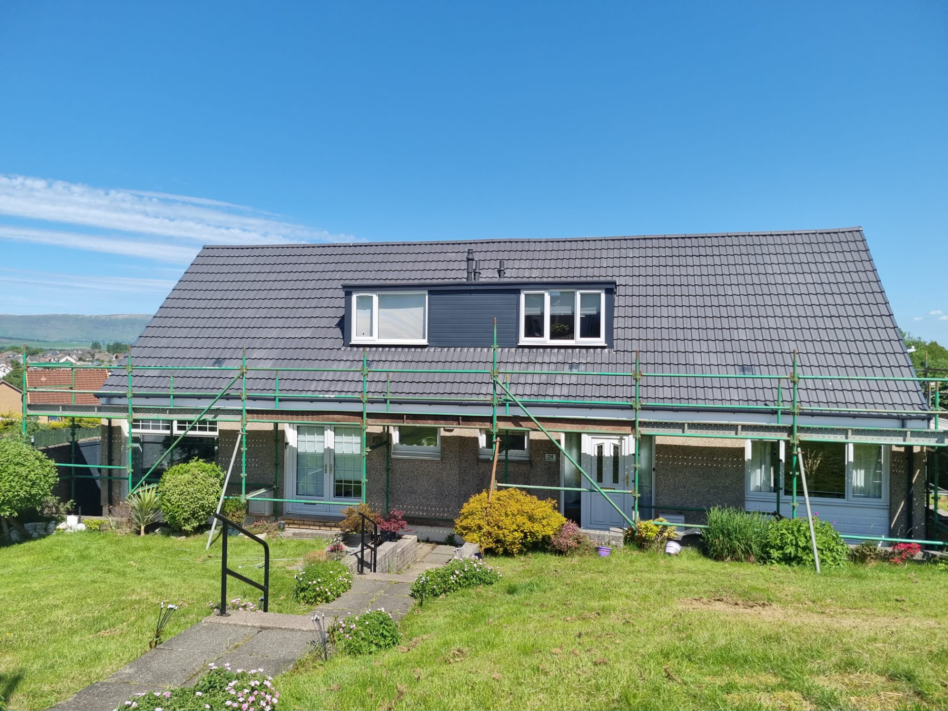 Semi-detached home with a newly tiled grey roof and dormer, scaffolding still in place