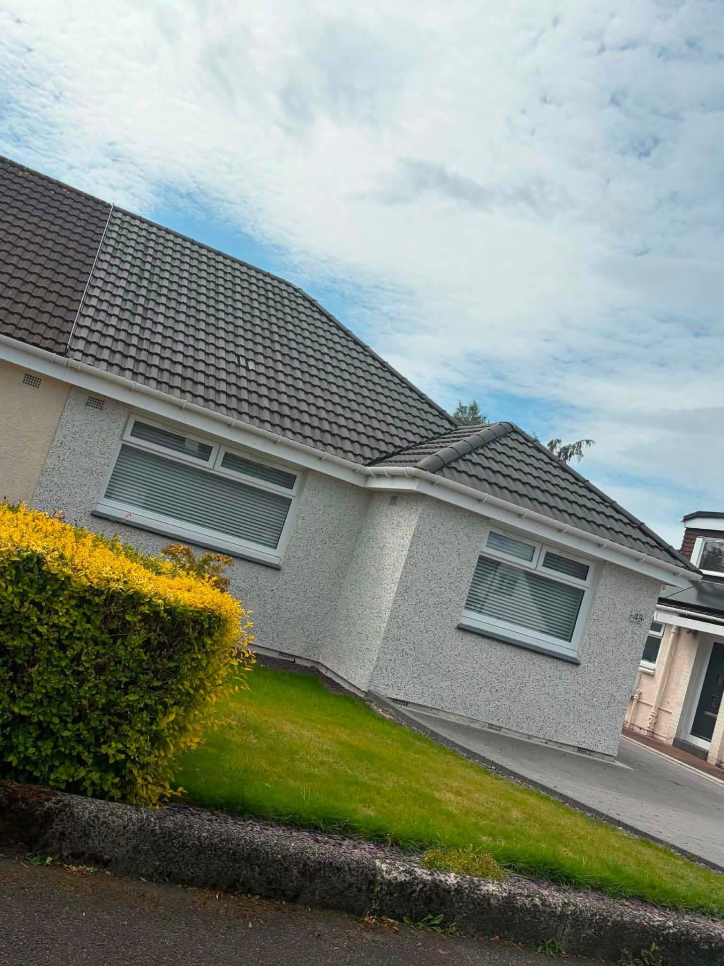Bungalow with newly laid grey roof tiles and white roughcast walls