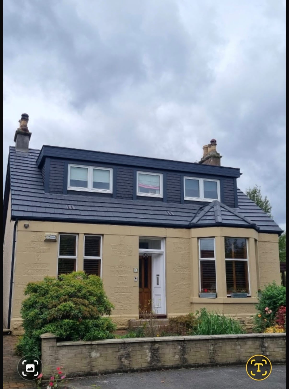 Detached sandstone house with a dark tiled roof and full-width dormer